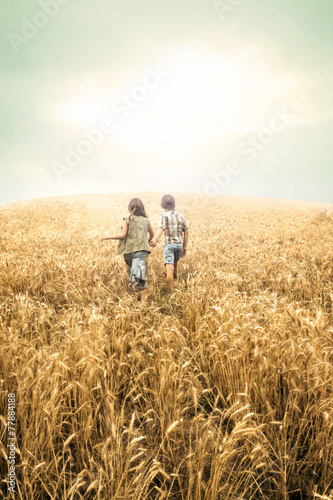 children running into wheat to the sunset
