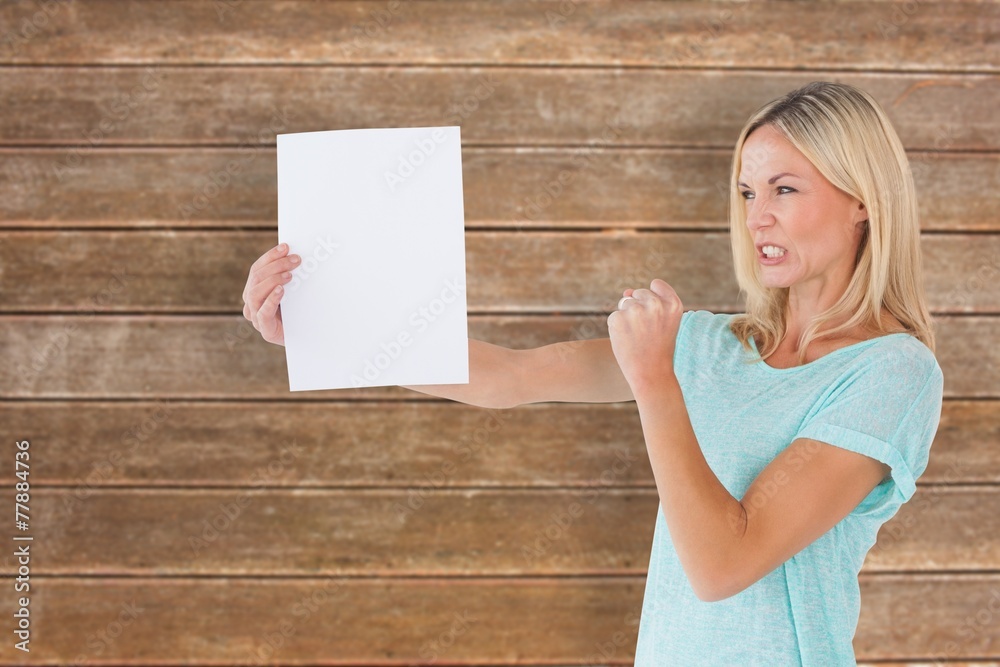 Composite image of angry woman holding piece of paper Composite image of angry woman holding piece of paper