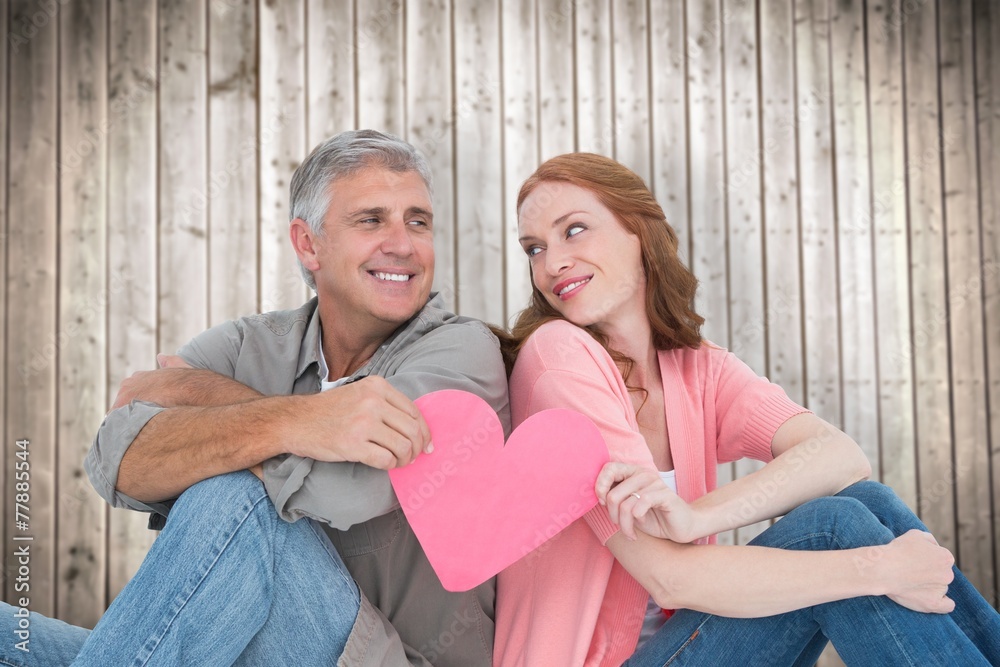 Composite image of casual couple holding pink heart