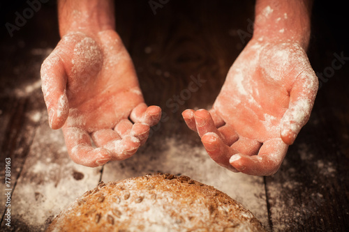 Baker hands with fresh bread on table