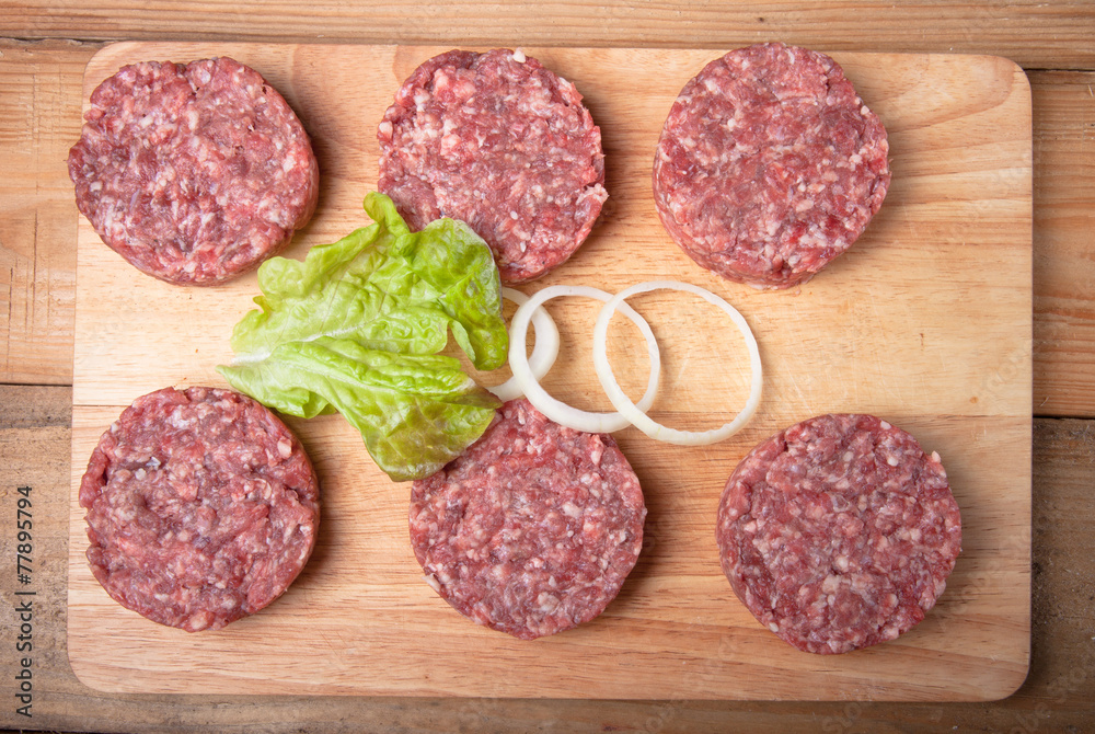 Raw cutlet of minced meat with leaf of salad and rings of onion Raw cutlet of minced meat with leaf of salad and rings of onion