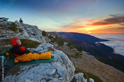 girl sitting on a cliff in mountains at sunrise