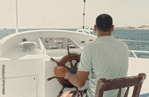 Captain of a yacht sitting by the steering wheel
