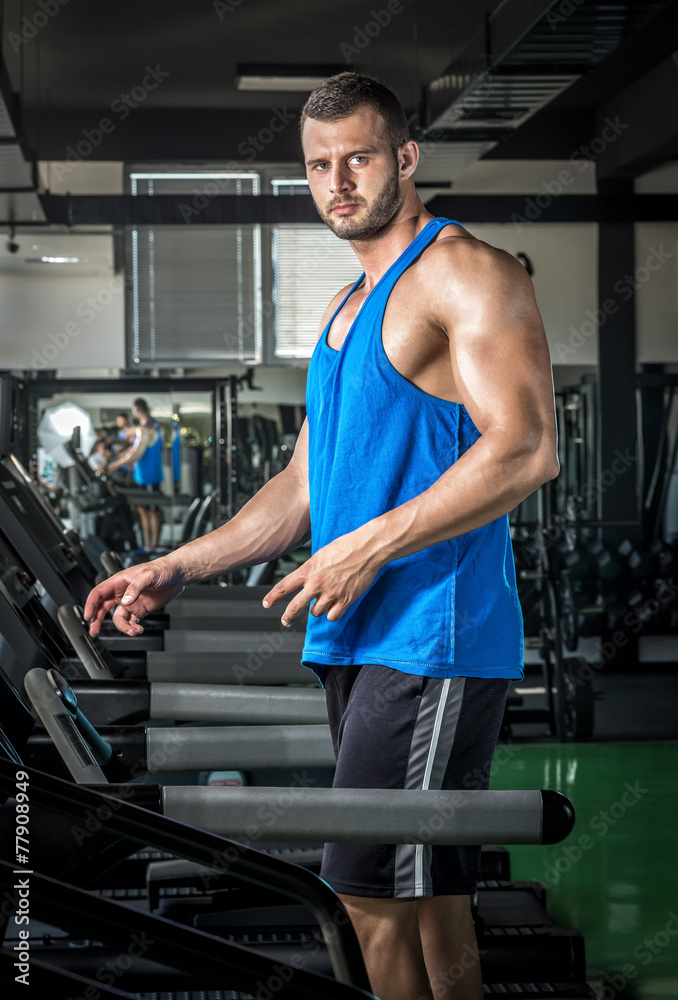 Young man running at treadmill in gym Young man running at treadmill in gym