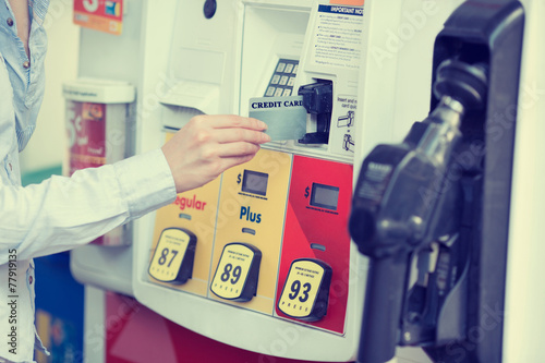 Woman hand swiping credit card at gas pump station photo