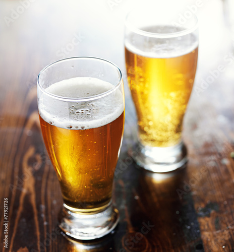 Vászonkép fresgly poured beer in mugs on top of wooden table