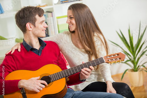 Attractive couple sitting on a couch with a guitar