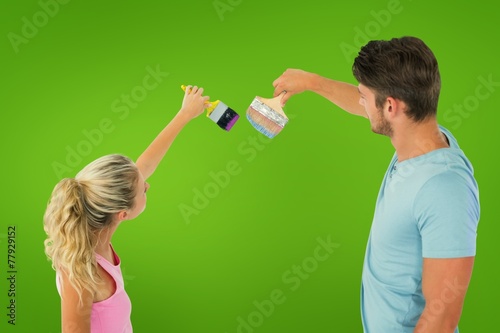 Composite image of young couple painting with brushes