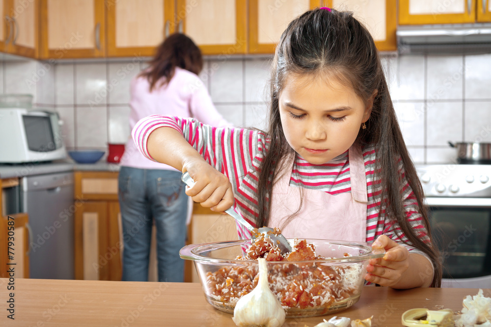 Mother and daughter prepare meat for lunch Mother and daughter prepare meat for lunch
