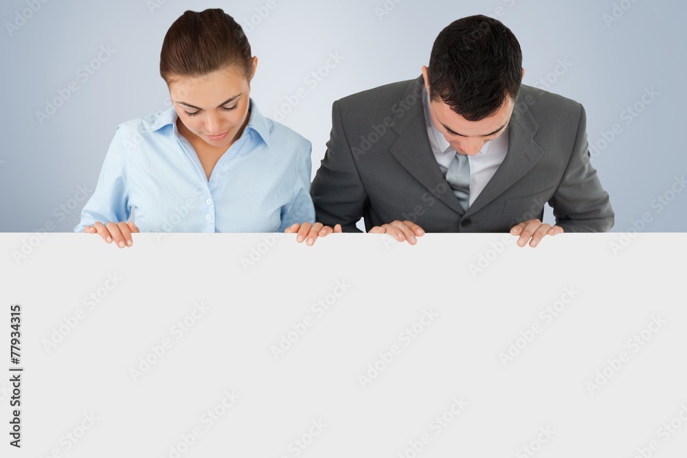 Business partners looking down at sign they a are holding Business partners looking down at sign they a are holding