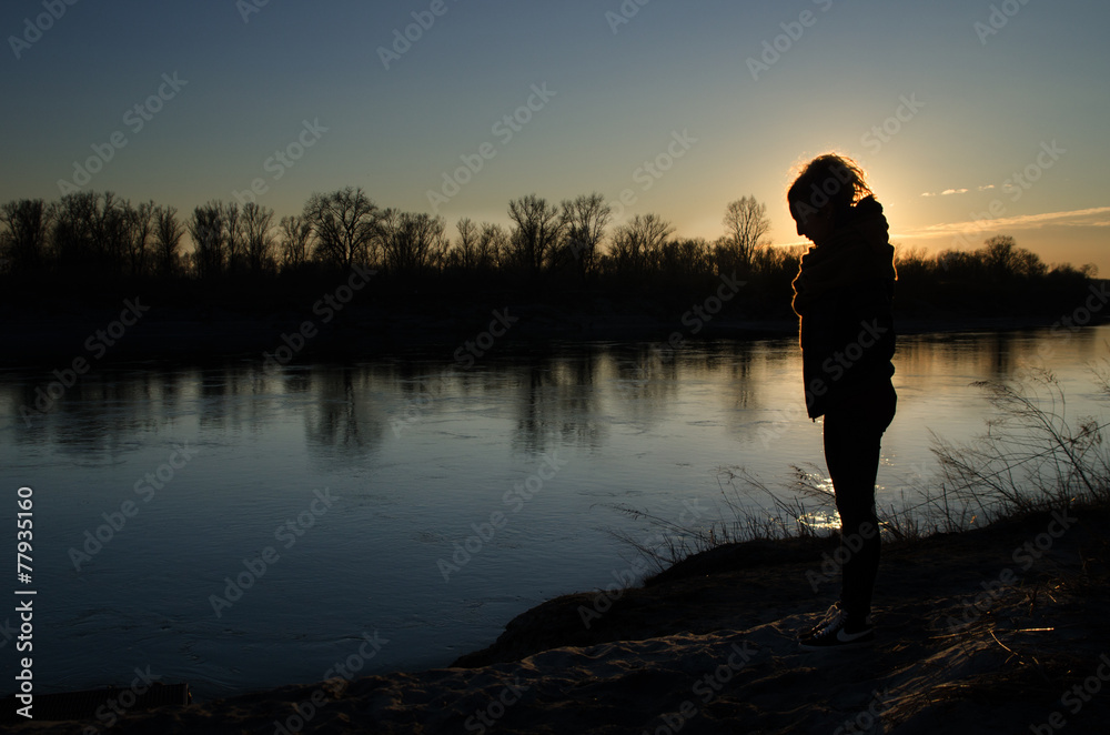 Young girl at sunset on the river bank