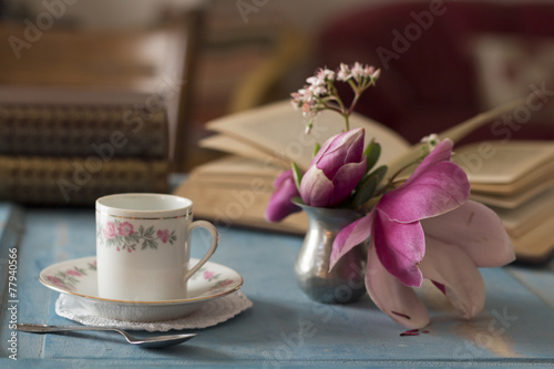 A pretty coffee cup and a opened book on a wooden table