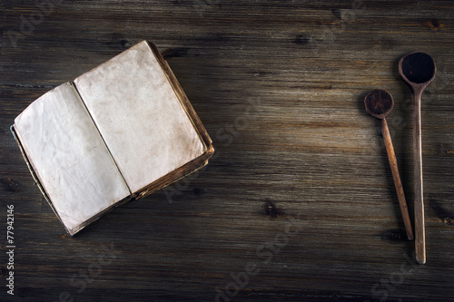 Old open book without text old wooden spoon on a wooden table