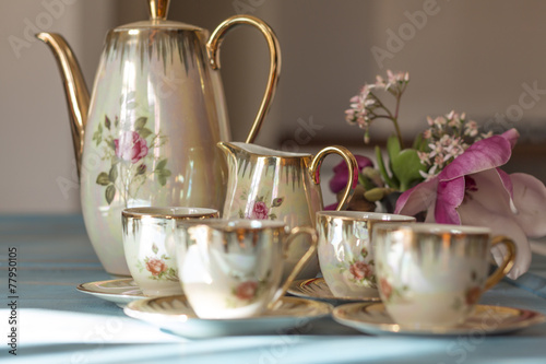 Vintage tea cups with teapot on old wooden table.