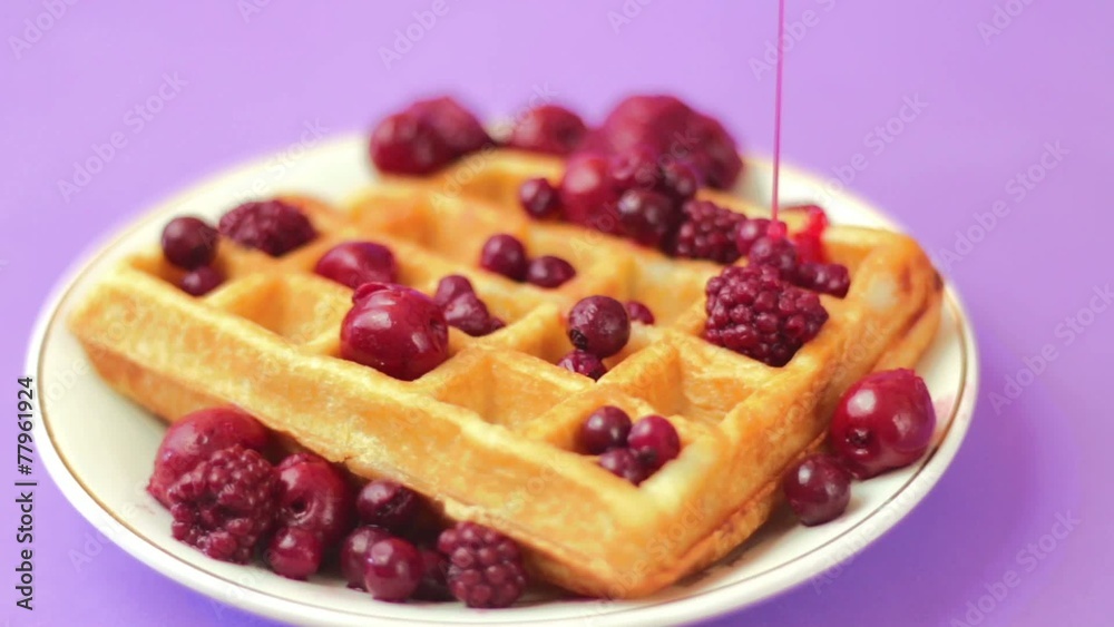 Pouring strawberry syrup on waffle with red berries Pouring strawberry syrup on waffle with red berries