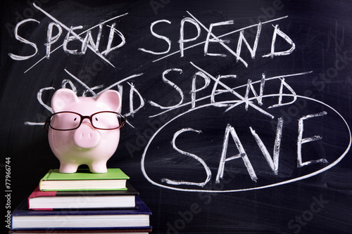Piggy Bank piggybank wearing glasses with spending money and savings plan message written on a blackboard or chalk board photo