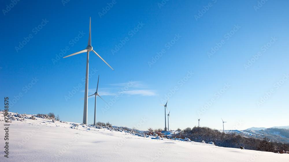 Fototapeta premium Typical windmill or aerogenerator of aeolian energy on snowy lan