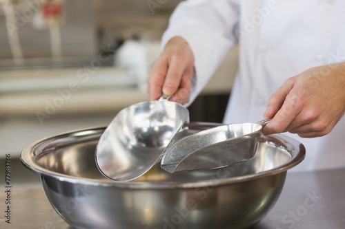 Baker holding scoops over bowl