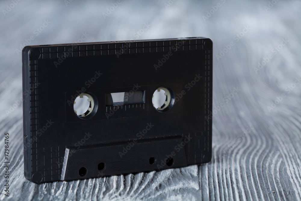Obraz premium Black audio cassette on the gray wooden background.