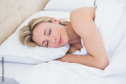 Smiling blonde woman resting in bed