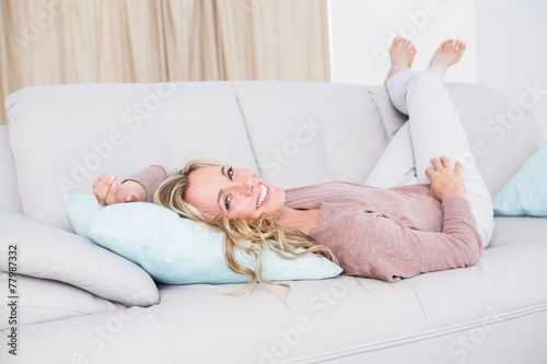 Smiling blonde lying on couch relaxing
