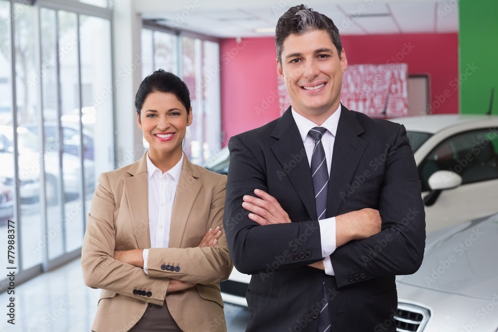 Smiling colleagues standing with arms crossed Smiling colleagues standing with arms crossed