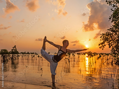 Woman practicing yoga on the beach near mangroves
