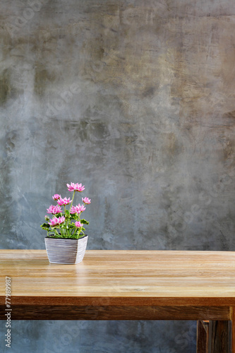 plastic flowers with pot on table in front of wall