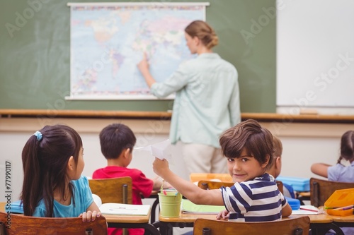 Naughty pupil about to throw paper airplane in class