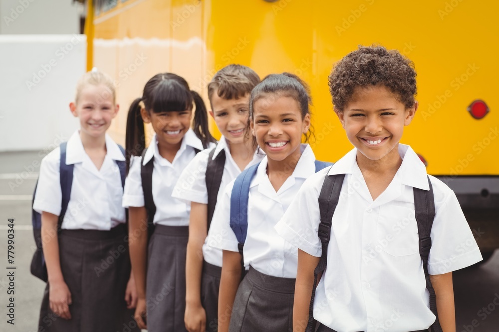 Cute schoolchildren smiling at camera by the school bus Cute schoolchildren smiling at camera by the school bus