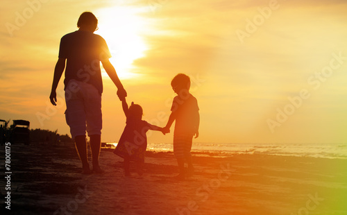 father and two kids walking at sunset