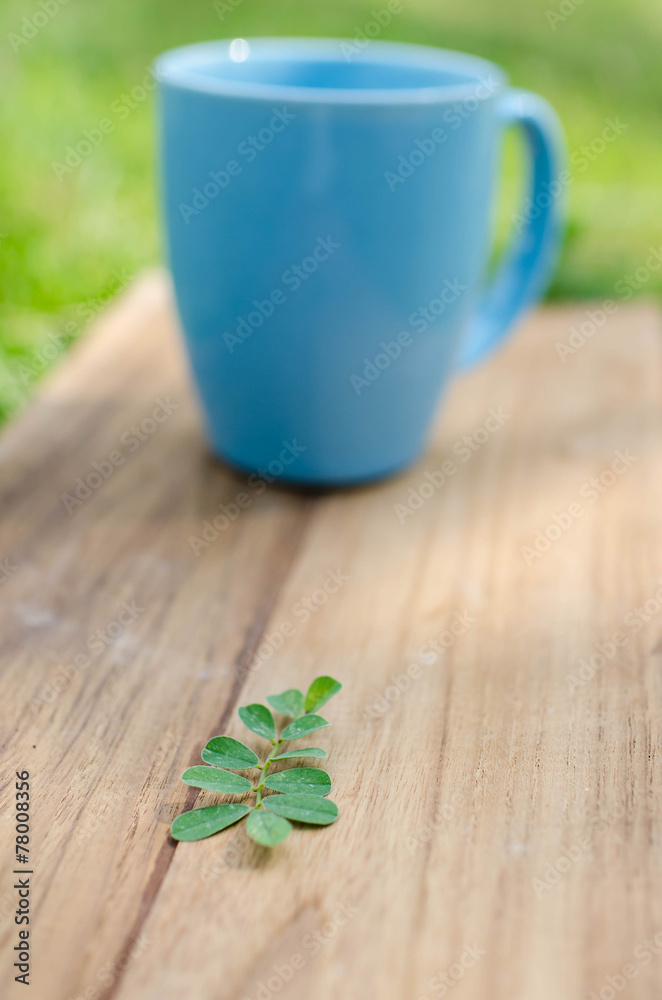 Blue mug on wooden board with green grass space. Blue mug on wooden board with green grass space.