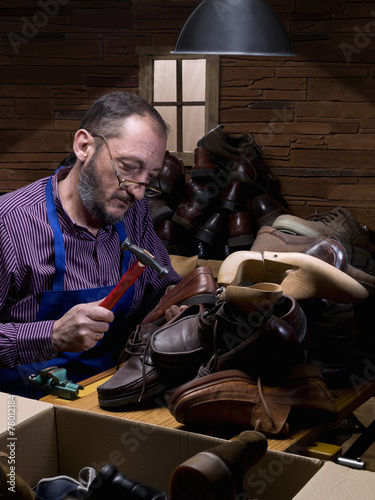 Old man  shoemaker  repairing old shoe in his workshop