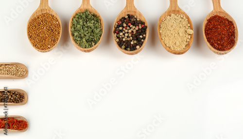 Fototapeta Naklejka Na Ścianę i Meble -  Different spices and herbs in wooden spoons isolated on white
