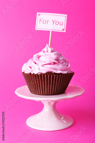 Delicious cupcake with inscription on pink background