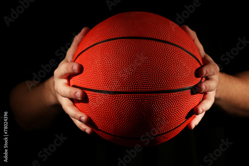 Basketball player holding ball, on dark background © Africa Studio