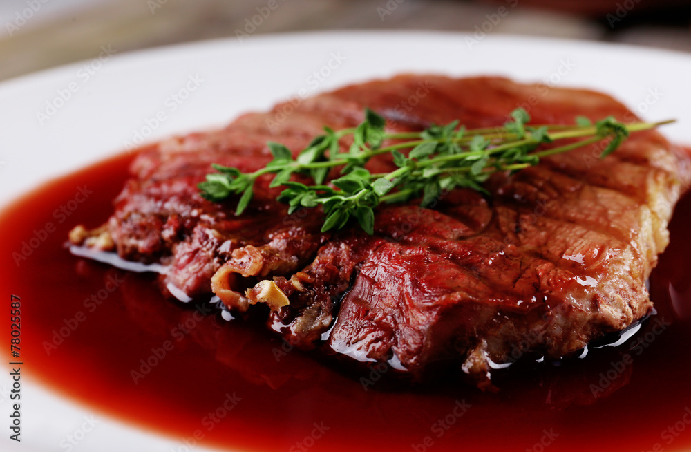 Grilled steak in wine sauce on plate close up Grilled steak in wine sauce on plate close up