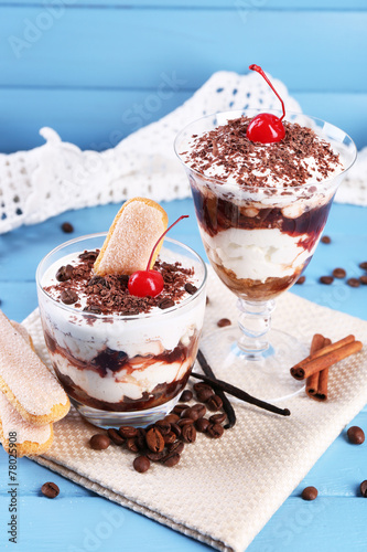 Tasty tiramisu dessert in glasses, on color wooden background