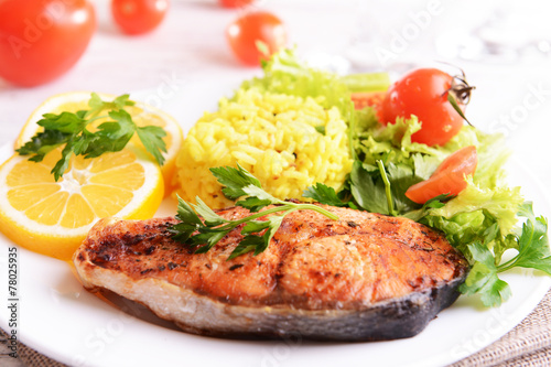 Tasty baked fish with rice on plate on table close-up