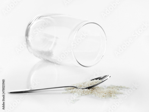 Remnants of rice in spoon with glass jar isolated on white photo