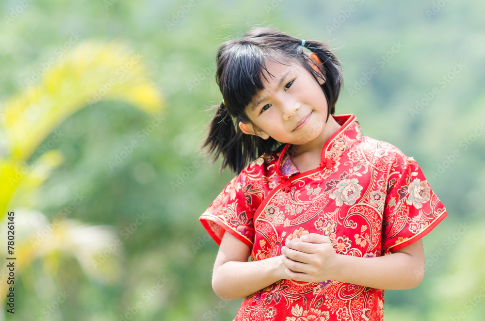 Asian child in traditional Chinese cheongsam with nature backgro Asian child in traditional Chinese cheongsam with nature backgro