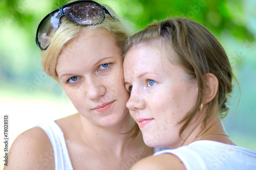 Two girls in the summer park one looks into a camera