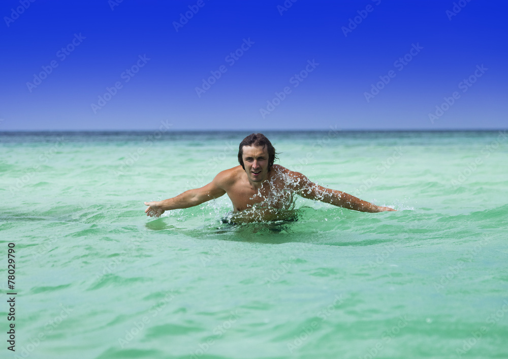 Young sports guy swimming in the turquoise water
