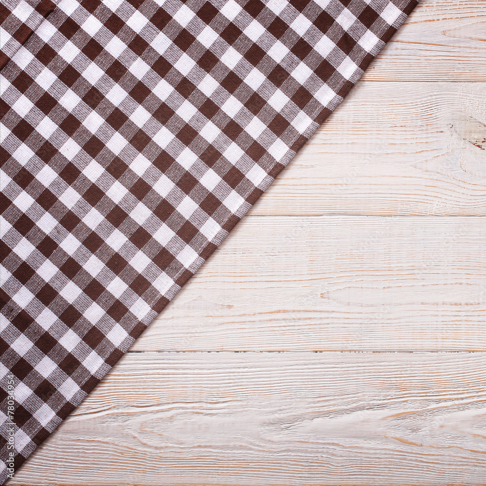 Top view of checkered tablecloth on white wooden table.