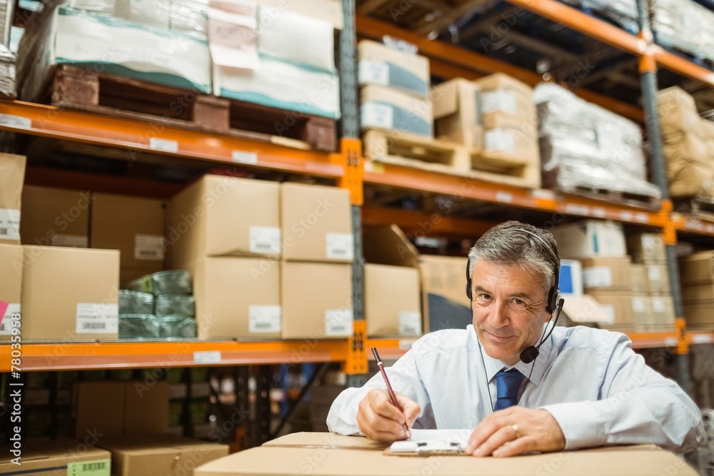 Fototapeta premium Manager looking at camera while writing on clipboard