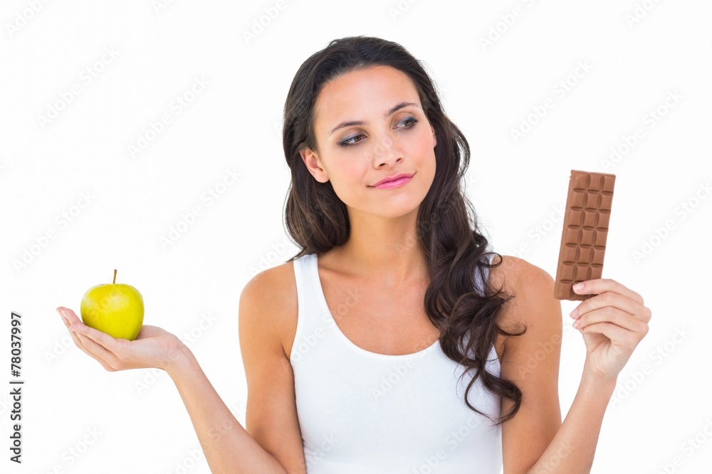 Pretty brunette deciding between apple and chocolate Pretty brunette deciding between apple and chocolate
