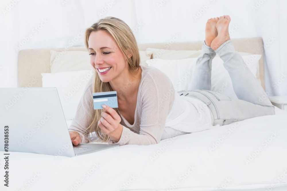 Cheerful blonde shopping online on the bed Cheerful blonde shopping online on the bed