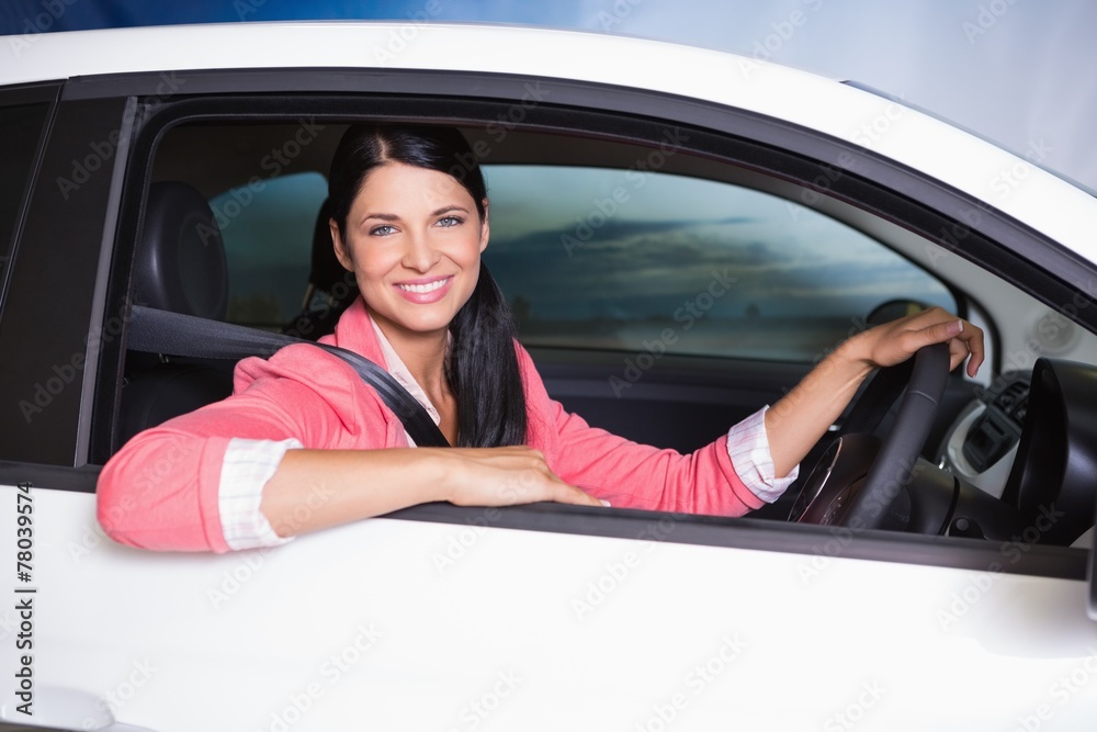 Smiling customer sitting at the wheel of a car for sale