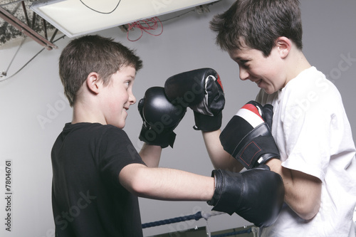 young boy with black boxing gloves fight with is brother photo