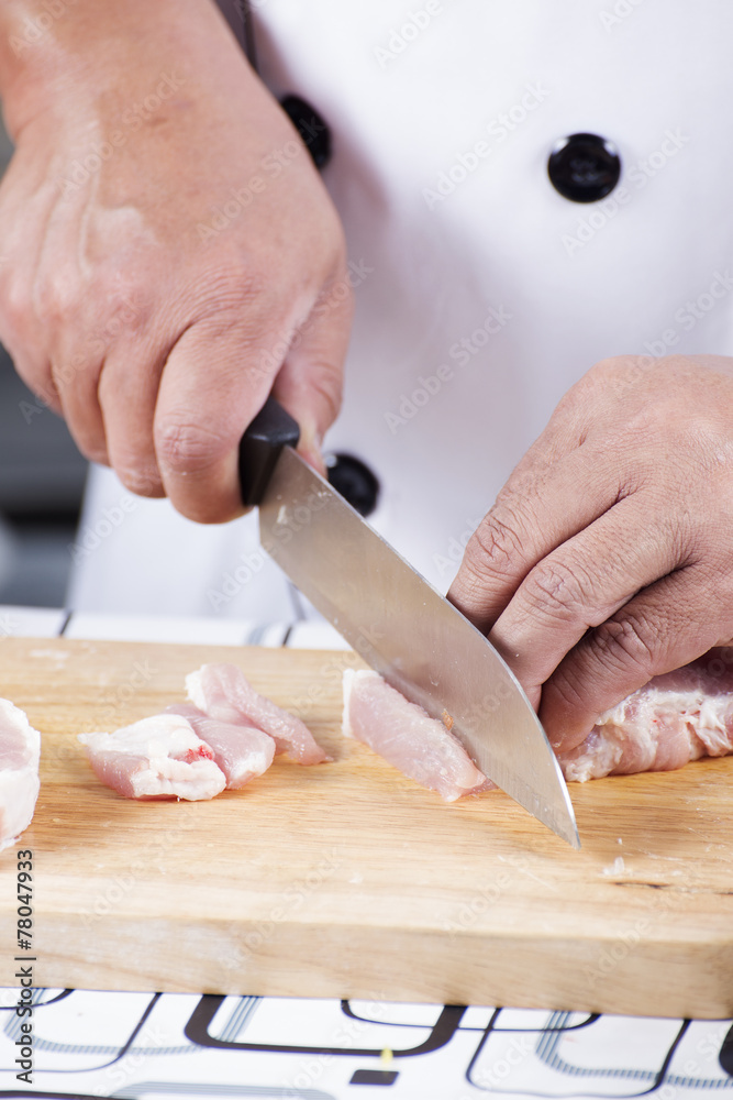 Chef cutting raw pork on wooden board